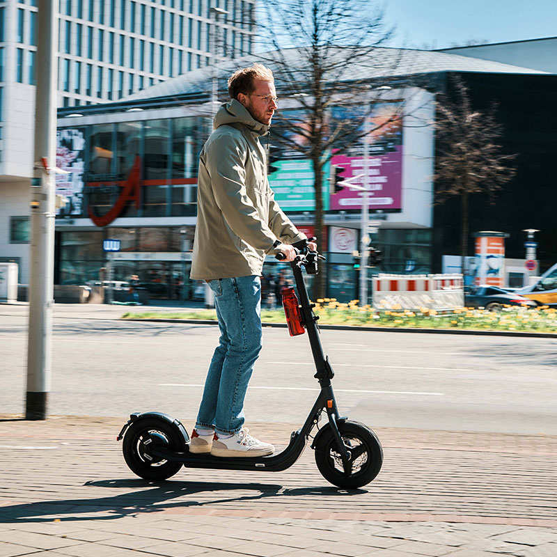 FIDLOCK-Webseite-TWIST-bottle-700-life-rot-mit-uni-base-am-E-Scooter-fahrend