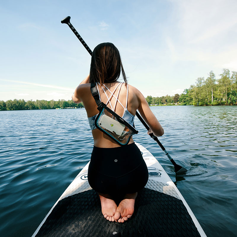 FIDLOCK-HERMETIC-sling-bag-transparent-outdoor-umgeschnallt-über-die-schulter-SUP-frau-knieend